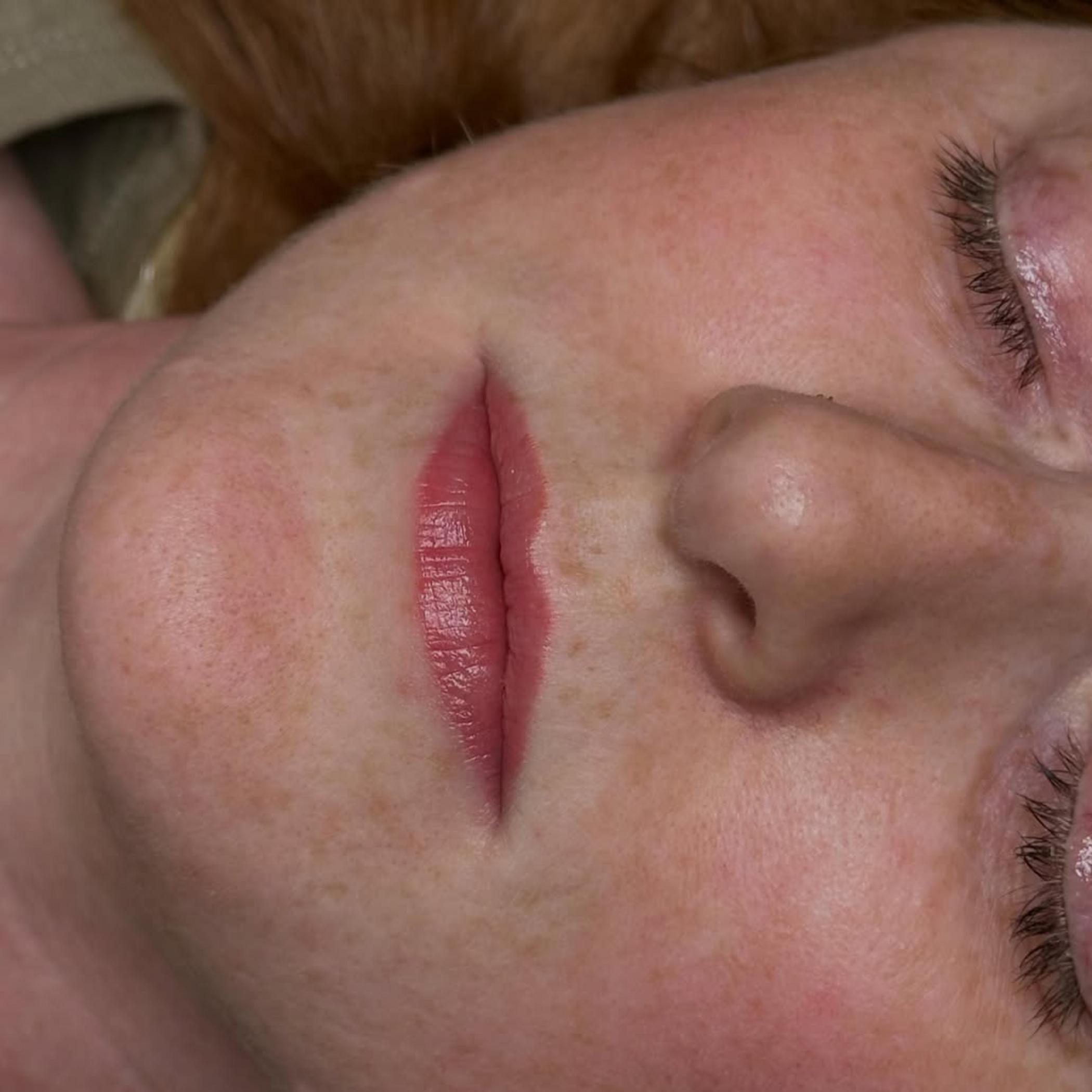 technician applying lip tattoo men